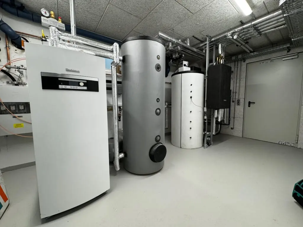 Technikraum des Neubaus mit bodenstehender Buderus-Wärmezentrale, Speichern und gedämmten Rohrleitungen