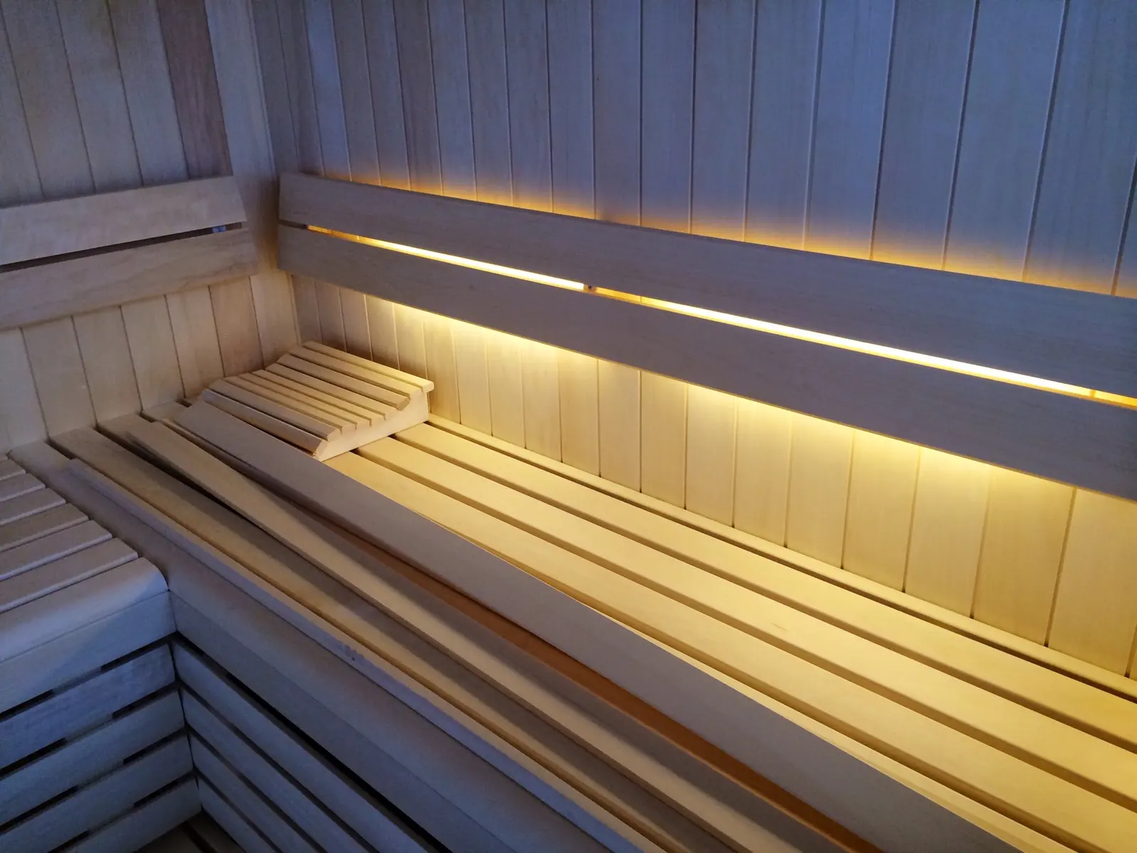 Helle Saunabänke mit LED-Lichtband hinter der Rückenlehne