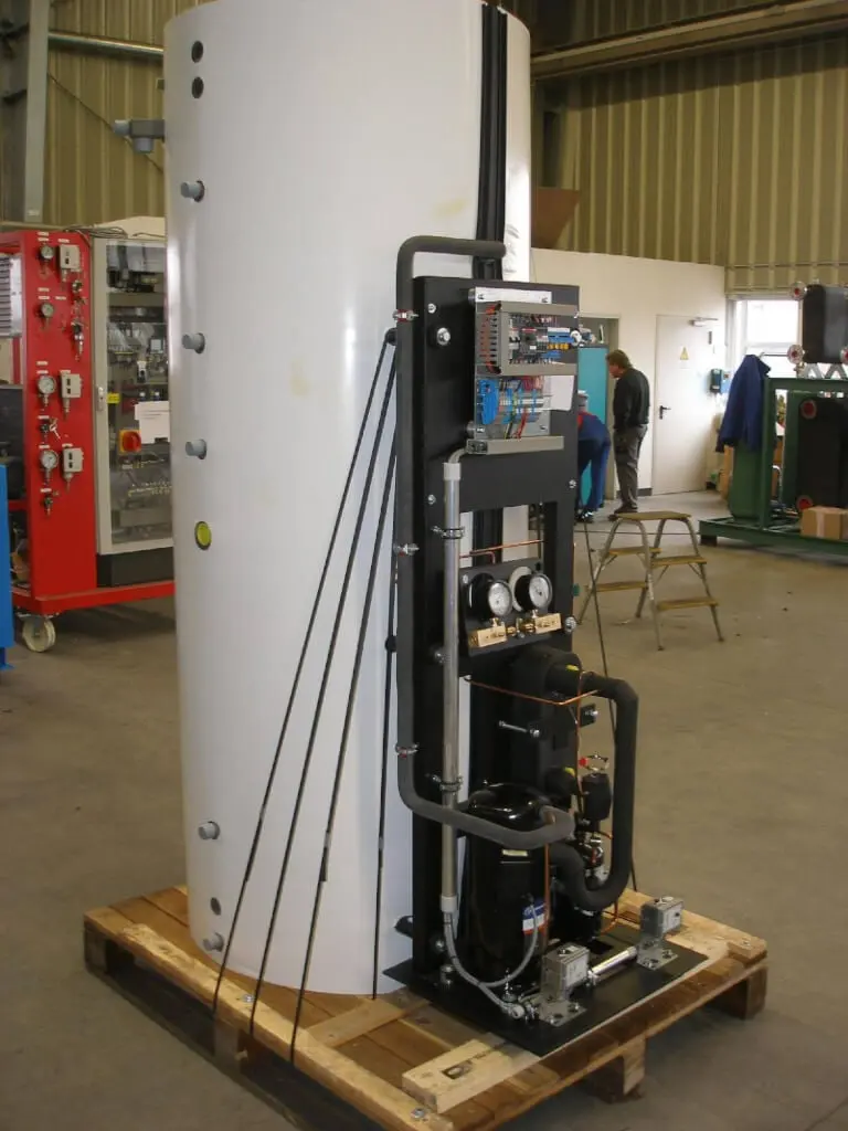 Die fertig montierte Eigenbau-Wärmepumpe mit weißem Pufferspeicher und Technikgestell auf einer Palette in der Werkhalle