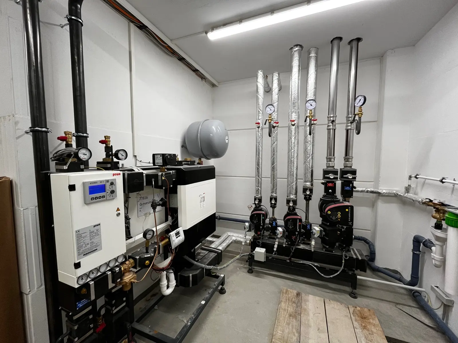 Fernwärme-Übergabestation mit Regelung, Umwälzpumpen und gedämmten Rohrleitungen im Technikraum